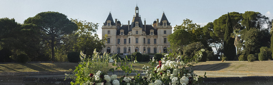 Vue d’ensemble d’un château accueillant un mariage de luxe dans ses jardins.