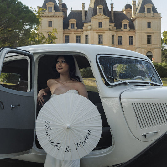 Mariée tenant une ombrelle de mariage personnalisée lors d’une séance photo, accessoire iconique et ultra photogénique.