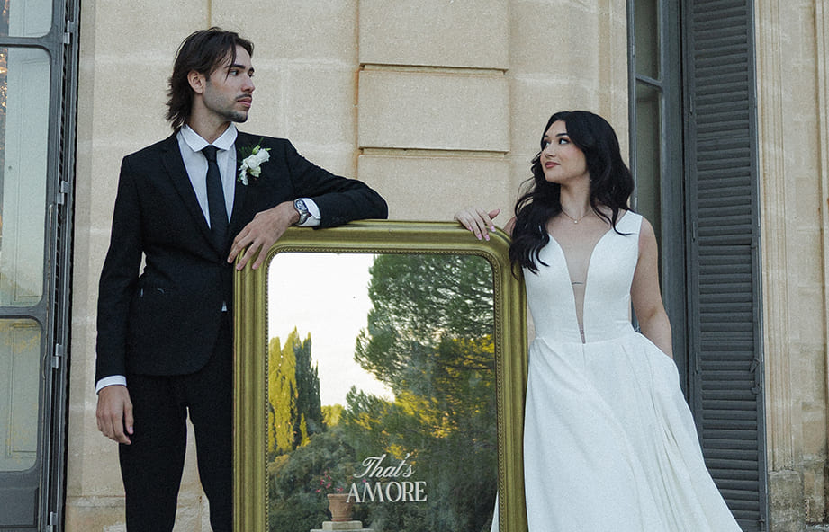 Mariés posant devant un miroir de signalétique élégante dans un château.