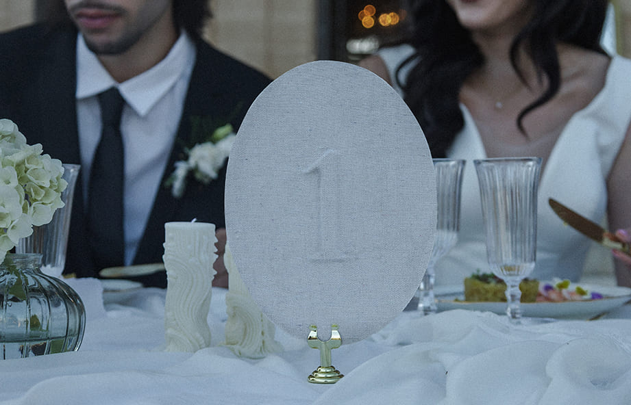 Numéro de table en tissu posé sur une table de mariage élégante au château.