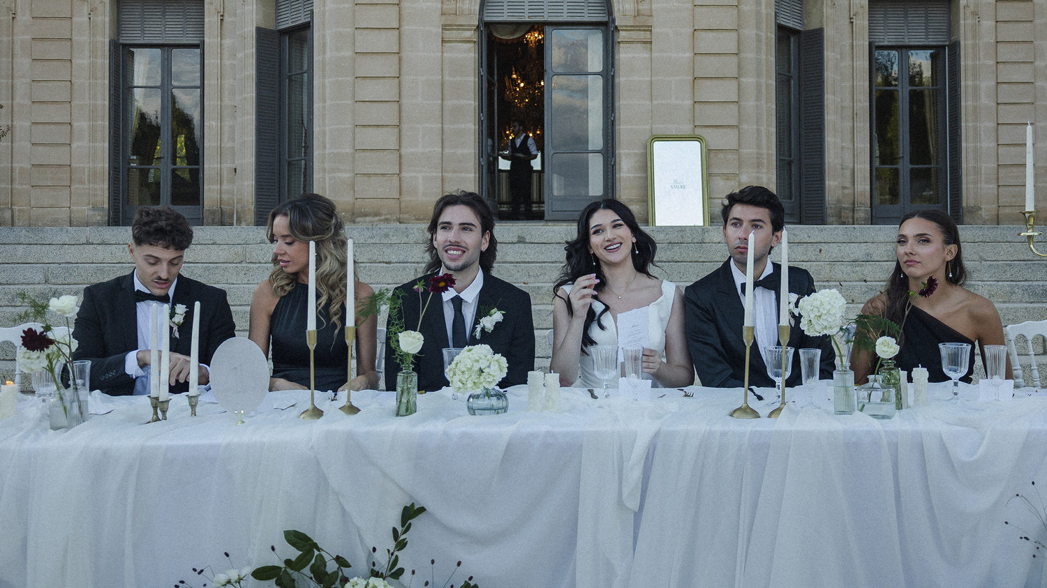 Table cocktail de mariage au château décorée de fleurs blanches et bougies dorées.